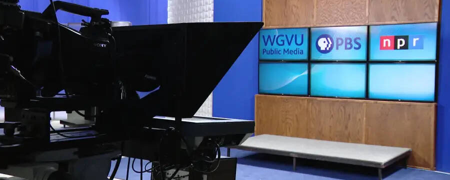 Television studio with a broadcast camera and WGVU Public Media PBS NPR on a digital screen.